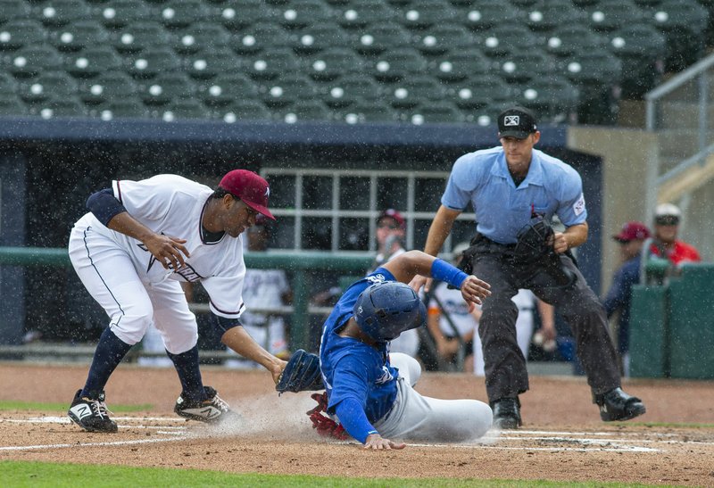 Special to NWA Democrat-Gazette/DAVID BEACH Ofreidy Gomez of the Naturals applies the tag to Christian Santana of the Drillers Sunday during a brief rain storm at Arvest Ballpark.