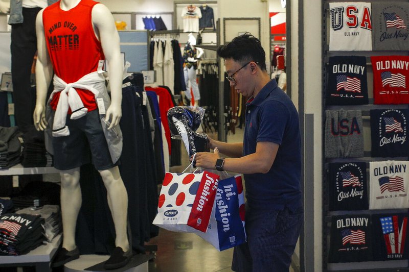 A man buys clothes from an American clothing store having a promotion sale at a shopping mall in Beijing, Monday, July 15, 2019. China's economic growth sank to its lowest level in at least 26 years in the quarter ending in June, adding to pressure on Chinese leaders as they fight a tariff war with Washington. (AP Photo/Andy Wong)