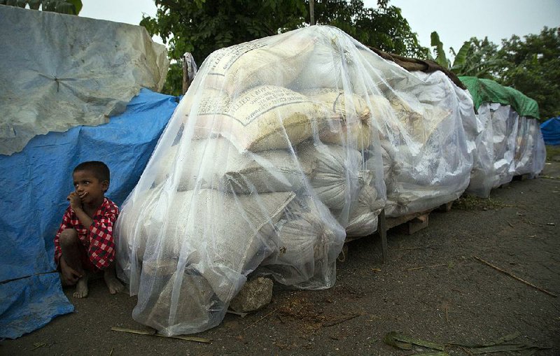 A boy crouches near flood-relief supplies Monday in a village east of Gauhati, India.