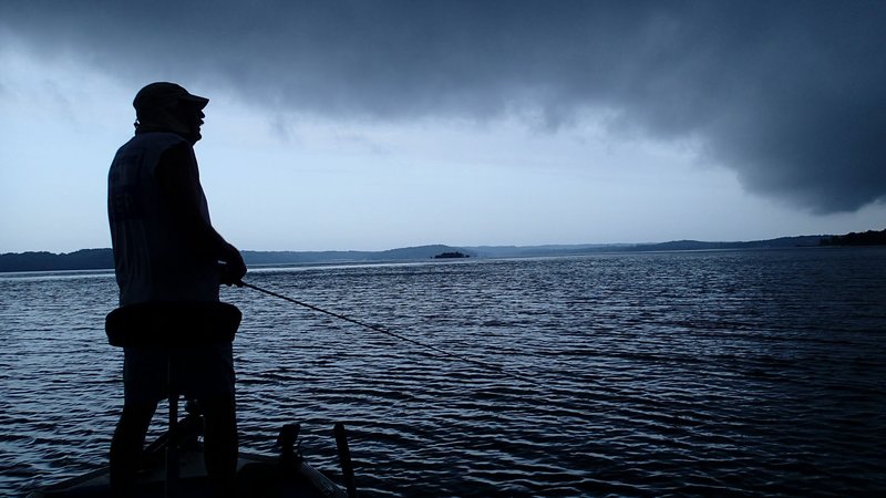 NWA Democrat-Gazette/FLIP PUTTHOFF Dwayne Culmer reels in his last cast July 5 2019 at Beaver Lake before high-tailing it back to the ramp as a storm rolls in.