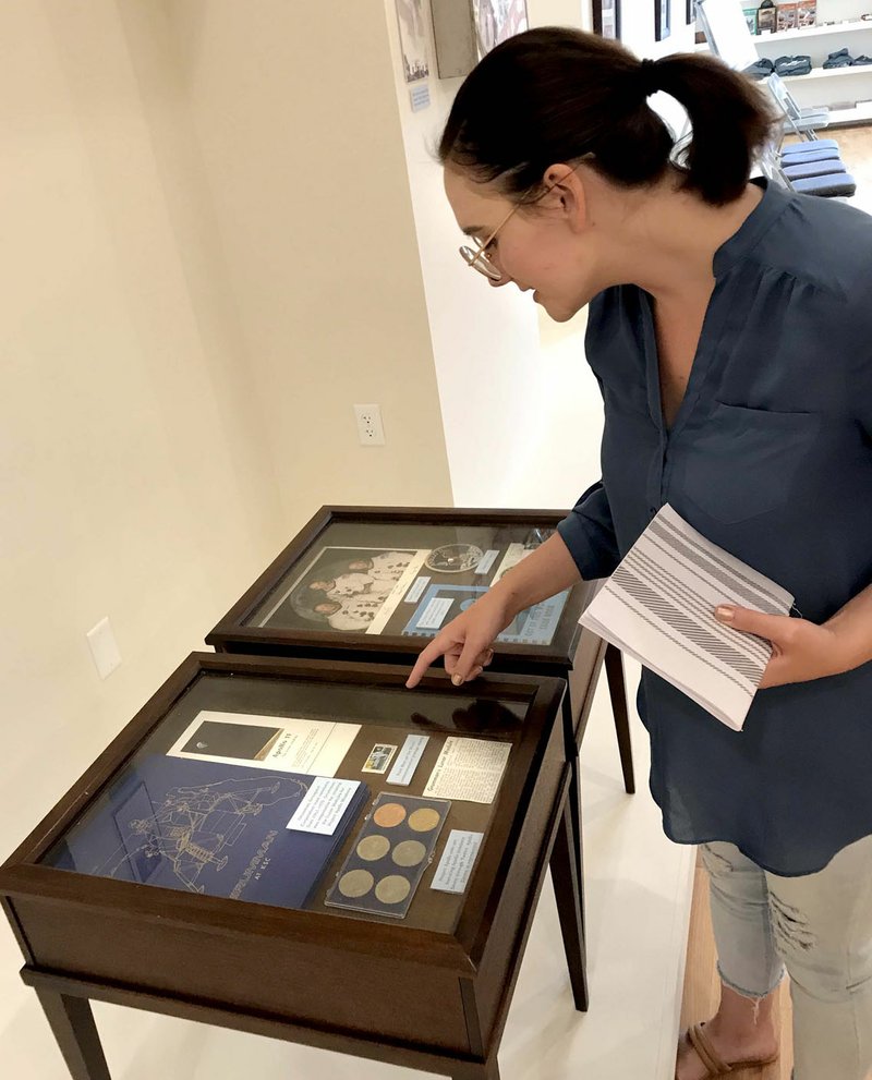 Janelle Jessen/Herald-Leader Amber Black, Siloam Springs Museum director of programming and media, looked over some of the items on loan from Judy Omo for the Apollo 11 memorial exhibit. The display includes coins, stamps, a letter addressed to Omo from the Kennedy Space Center on the morning of the launch and a signed photograph of astronauts Buzz Aldrin, Neil Armstrong and Michael Collins, along with many other items.