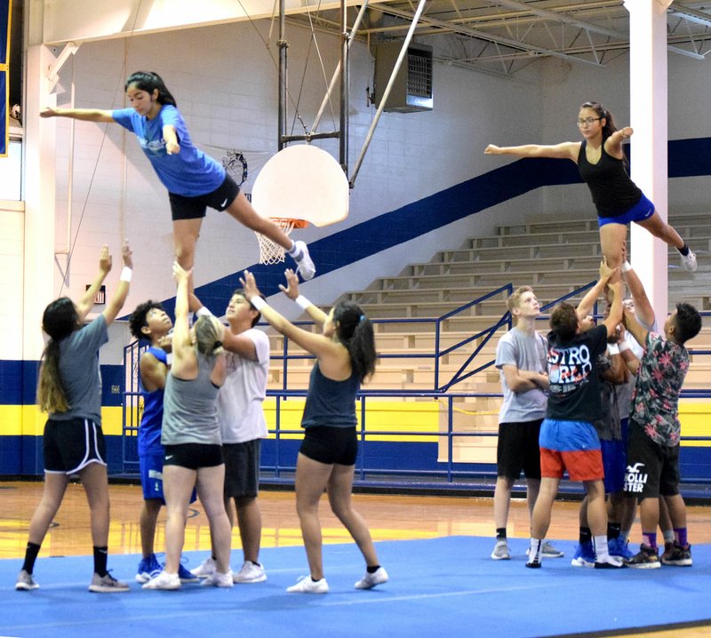 Westside Eagle Observer/MIKE ECKELS With their bases and spotters performing perfectly, flyers Stephanie Sandoval (upper left) and Kaylee Morales (upper right) hold a classic Arabesque maneuver during the morning training session of the July 12 Bulldog Cheer Camp in Decatur.