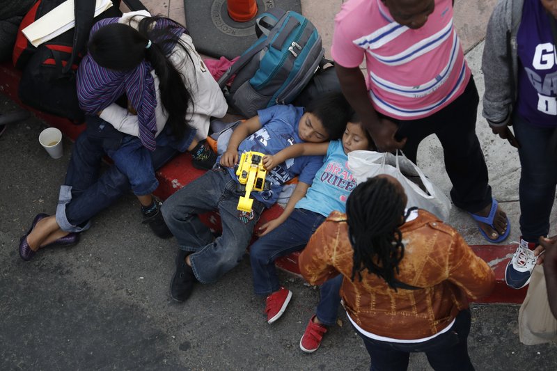 People wait to apply for asylum in the United States along the border, Tuesday, July 16, 2019, in Tijuana, Mexico. Dozens of immigrants lined up Tuesday at a major Mexico border crossing, waiting to learn how the Trump administration's plans to end most asylum protections would affect their hopes of taking refuge in the United States. (AP Photo/Gregory Bull)