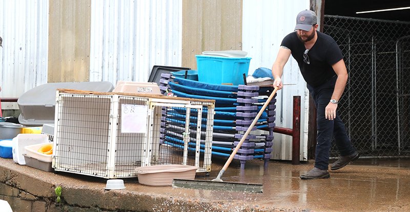 The Sentinel-Record/Richard Rasmussen CLEANING UP: Volunteer Bobby Hanks squeegees water out of the Humane Society of Clark County on Walnut Street in Arkadelphia Tuesday.