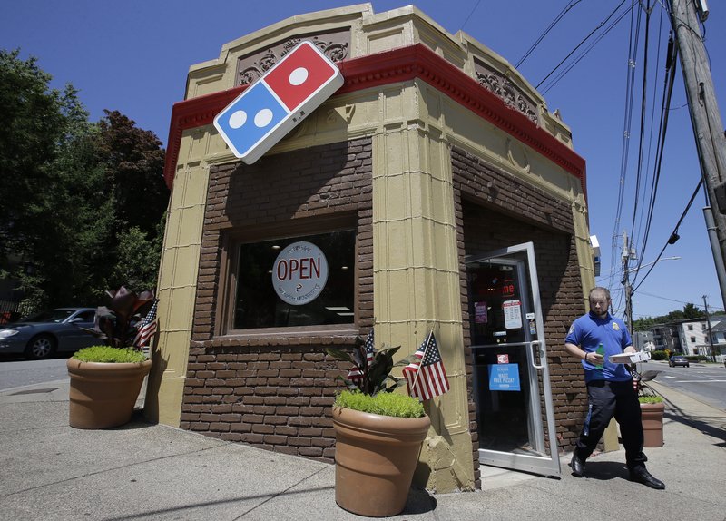 In this Monday, July 15, 2019 photo a customer departs a Domino's location holding food items, in Norwood, Mass. (AP Photo/Steven Senne)