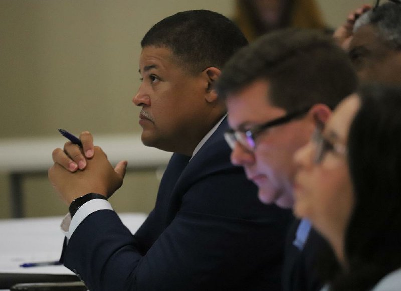 Pulaski County Sheriff Eric Higgins (left) listens to a  presentation about gunshot detection along with Little Rock City Directors Lance Hines and Capi Peck at Wednesday’s public safety summit. 