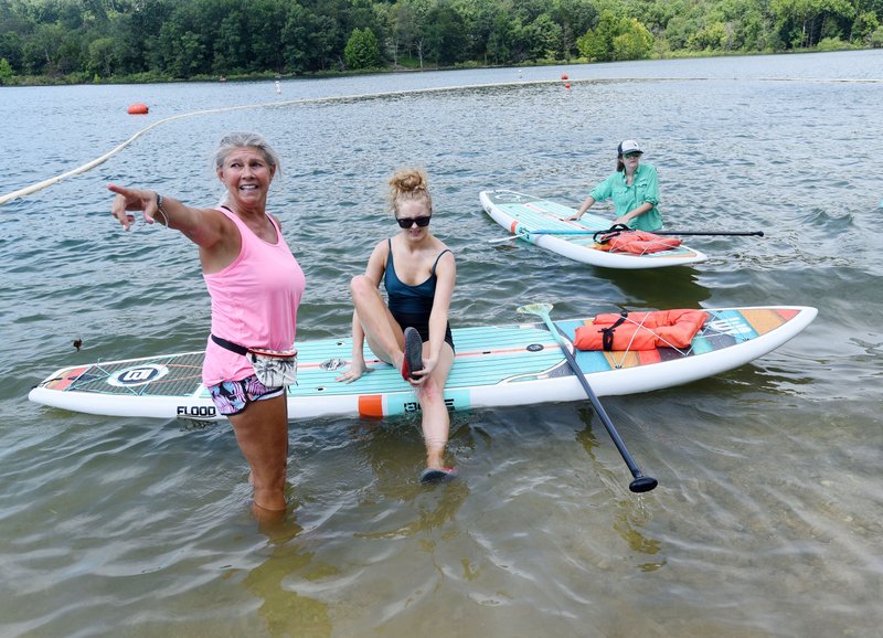 Melody Elliott, a stand-up paddleboard instructor, teaches students Wednesday how to paddle the long boards during a free paddle board clinic hosted by the Beaver Watershed Alliance. The event, held at Rocky Branch park on Beaver Lake, is one of several the alliance hosts in July, which is Lakes Appreciation Month. A lake cleanup set for Saturday at the Arkansas 12 bridge launch ramp has been canceled because of high water. NWA Democrat-Gazette/FLIP PUTTHOFF