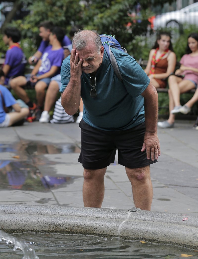 Russ Wilson splashes water on his face from a fountain in New York, Wednesday, July 17, 2019. The heat wave that has been roasting much of the U.S. in recent days is just getting warmed up, with temperatures expected to soar to dangerous levels through the weekend. (AP Photo/Seth Wenig)