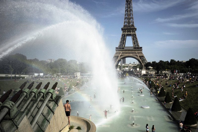 People cool off in the fountains of the Trocadero gardens, in front of the Eiffel Tower, in Paris, Friday, June 28, 2019. Schools are spraying kids with water and nursing homes are equipping the elderly with hydration sensors as France and other nations battle a record-setting heat wave baking much of Europe. (AP Photo/Lewis Joly)