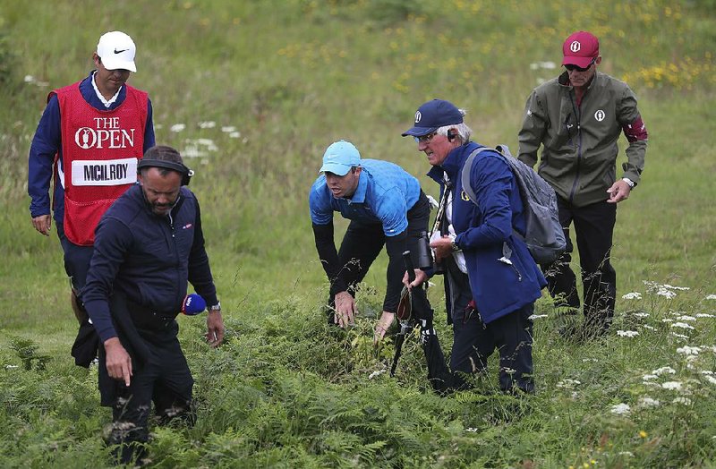 Rory McIlroy (middle) receives help as he looks for his ball in the long rough on the first hole during Thursday’s fi rst round of the British Open at Royal Portrush in Northern Ireland. McIlroy finished with a quadruple bogey on the hole and shot an 8-over 79 for the round.
