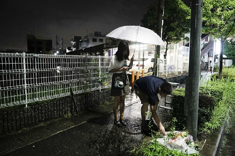 A couple places flowers today near a cordoned-off animation studio in Kyoto, Japan, where 33 people perished in a fire Thursday.