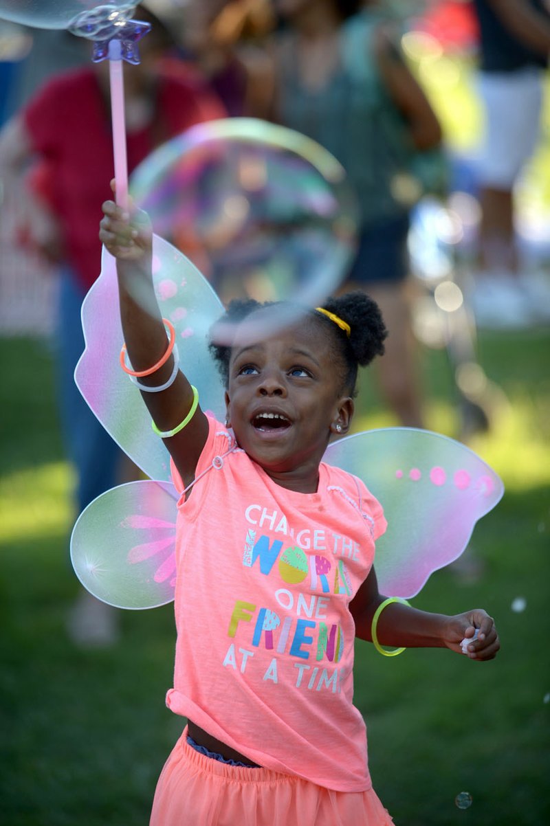 File Photo/ANDY SHUPE Zoe Brayan, 5, of Springdale pops soap bubbles with her wand during the 2018 Firefly Fling at the Botanical Garden of the Ozarks in Fayetteville.