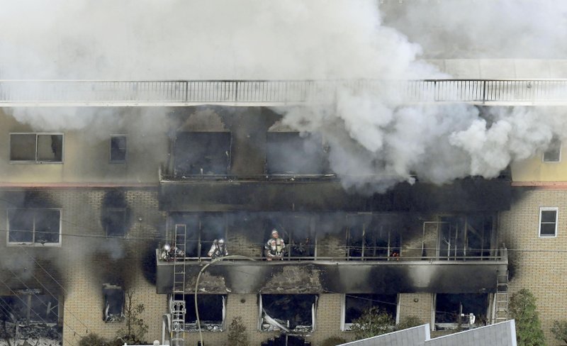 Firefighters work as smoke billows from a three-story building of Kyoto Animation in a fire in Kyoto, western Japan, Thursday, July 18, 2019. Kyoto prefectural police said the fire broke out Thursday morning after a man burst into it and spread unidentified liquid and put fire. (Kyodo News via AP)