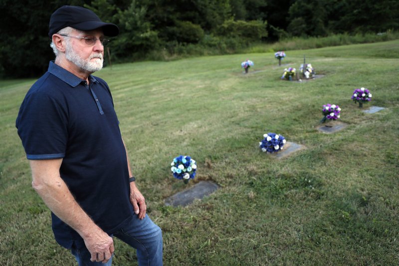 Eddie Davis stands beside the gravestone of his son Jeremy, furthest left, who died from the abuse of opioids, Wednesday, July 17, 2019, in Coalton, Ohio. Members of his family are buried in adjacent plots, including his parents and a sibling. (AP Photo/John Minchillo)