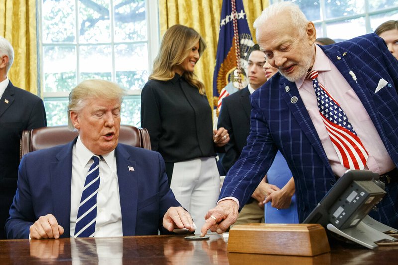 President Donald Trump receives a gift from Apollo 11 astronaut Buzz Aldrin, with first lady Melania Trump, during a photo opportunity commemorating the 50th anniversary of the Apollo 11 moon landing in the Oval Office of the White House, Friday, July 19, 2019, in Washington. (AP Photo/Alex Brandon)