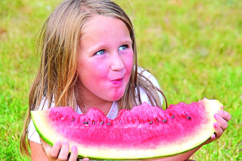 Snow Stephenson of Jonesboro takes a bite of her watermelon slice during the Free Watermelon Feast, part of the annual Cave City Watermelon Festival last year at Cave City Park.