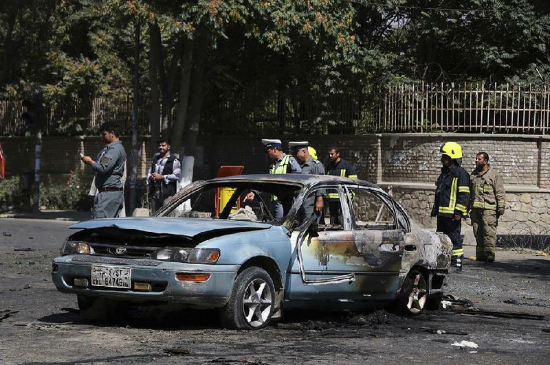 Afghan security forces stand guard near a car charred in an explosion Friday near the gates of Kabul University. 