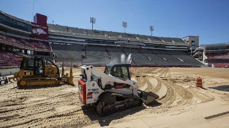 Crews work in preparation for grass to be placed on the playing surface at Reynolds Razorback Stadium in Fayetteville. The artificial surface was removed in April, and officials say they expect to have real grass in place by early August. 