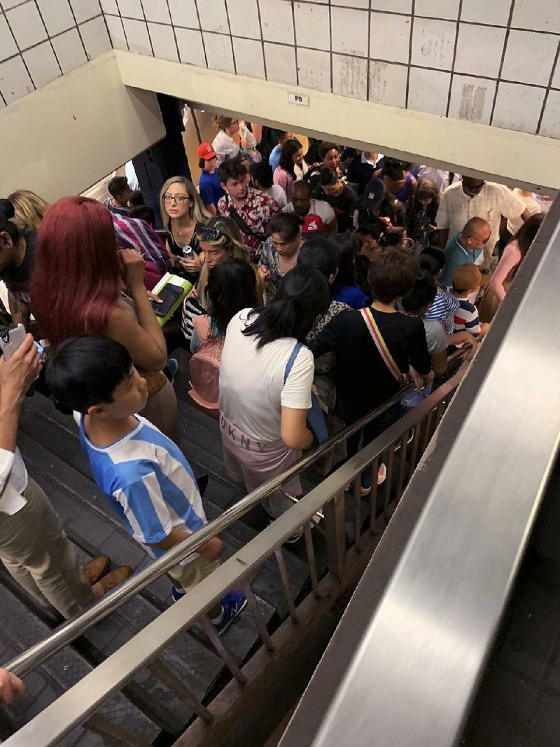 Commuters fill the stairs and line the platform at a New York City subway station Friday where train service on seven lines came to a halt. 