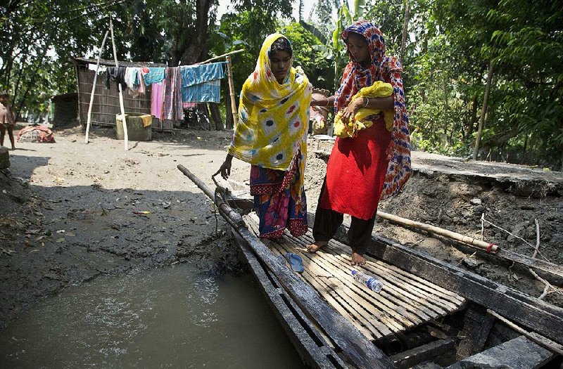 A woman  holds Imrana  Khatoon’s newborn baby Friday while helping Khatoon onto a boat to go to a hospital in Gagalmari, east of Gauhati, India. 