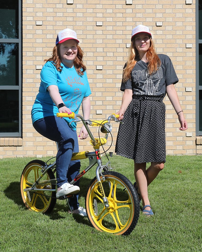 Hot Springs Advertising and Promotion Commission employees Katelynn Parks, left, and Alexis Hampo pose with a replica of the Strager Things bike Friday, July 19, 2019. (The Sentinel-Record/Richard Rasmussen)