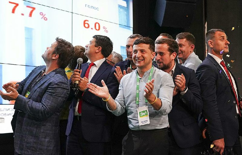 Ukrainian President Volodymyr Zelenskiy applauds with his team as they see the parliamentary election results Sunday at party headquarters in Kiev. 