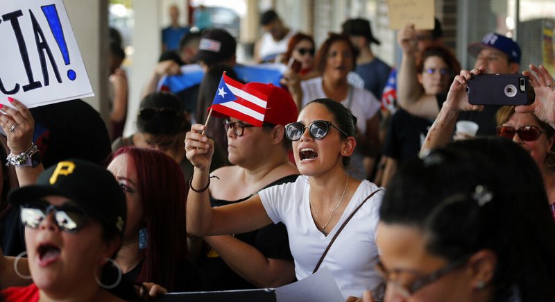 About 200-300 people from the North Texas (Dallas-Fort Worth area) Puerto Rican community gather to protest Gov. Ricardo Rossello outside the Adobo Puerto Rican Cafe in Irving, Texas, Sunday, July 21, 2019. Puerto Rico's embattled governor says he will not seek re-election but will not resign as the island's leader, though he will step down as head of his pro-statehood party. (Tom Fox/The Dallas Morning News via AP)