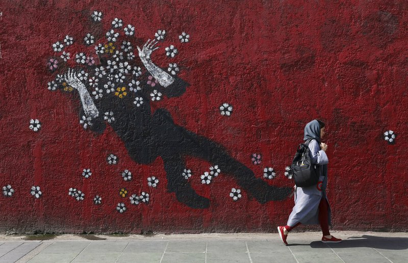 A woman walks past a mural in a sidewalk in downtown Tehran, Iran, Sunday, July 21, 2019. (AP Photo/Vahid salemi)