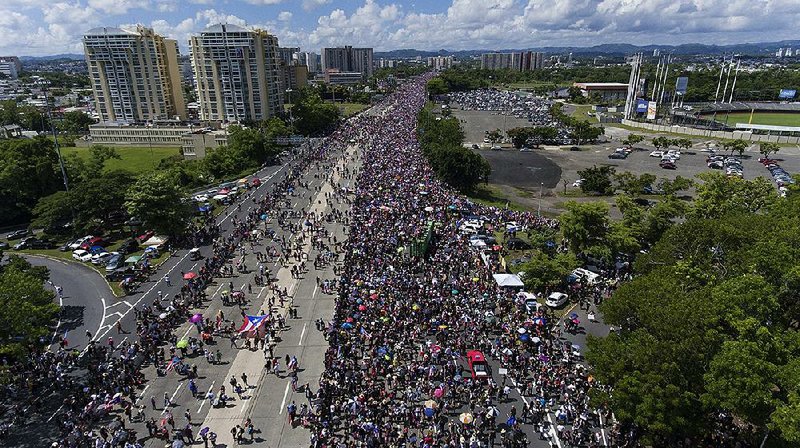 Demonstrators march Monday on Las Americas highway in San Juan, Puerto Rico, demanding the resignation of Gov. Ricardo Rossello. Protests against the governor began more than a week ago, after the leak of an obscenity-laced chat on a messaging app used by the governor and his closest aides. 