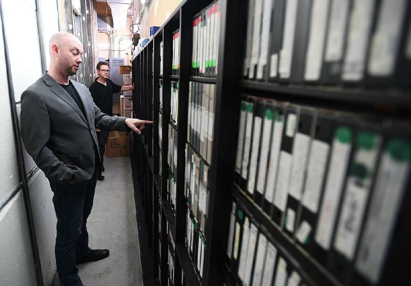 Dan Robinson, operational manager for Fayetteville Public Television, points out tapes Thursday at the station’s archive room. The public-access station has about 2,000 tapes and is looking for volunteers to help with a project to digitize its archives.