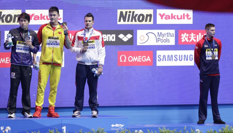 Britain's bronze medalist Duncan Scott, right, refuses to stand with gold medalist China's Sun Yang, second left, as silver winner Japan's Katsuhiro Matsumoto, left, and joint bronze medal winner Russia's Martin Malyutin pose on the podium following the men's 200m freestyle final at the World Swimming Championships in Gwangju, South Korea, Tuesday, July 23, 2019.