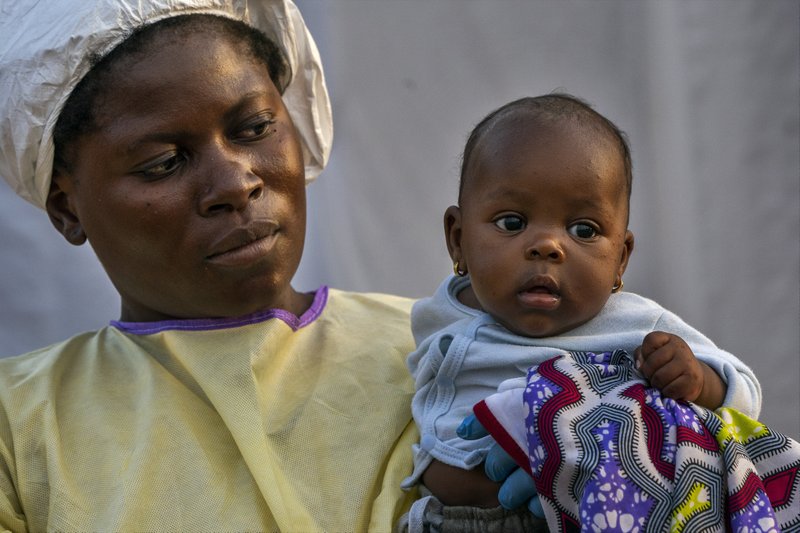 In this Wednesday, July 17, 2019 photo, 2-month-old Lahya Kathembo is carried by a nurse waiting for test results at an Ebola treatment center in Beni, Congo. Lahya became an orphan in a day. Her mother succumbed to Ebola on a Saturday morning. By sunset her father was dead. Her tests came back negative for Ebola. (AP Photo/Jerome Delay)