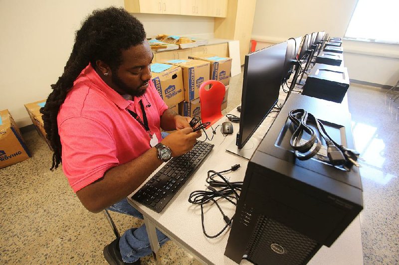 Gary Blanks II sets up computer equipment in a computer lab Friday at the new Jacksonville High School. More photos at www. arkansasonline.com/728jaxhs/
 