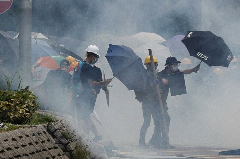 Protesters face off with tear-gas tossing riot police Saturday in the Yuen Long district in Hong Kong. 