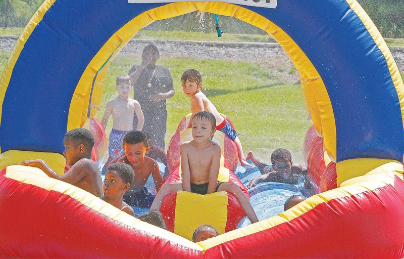 Children enjoy a bouncy house with sprinklers at Old City Park while attending Fun Day in the Park on Saturday. The event is a hosted by Jason Alan's Barbershop and is aimed at providing children with an entertaining day before they head back to school. (Terrance Armstard / News-Times)