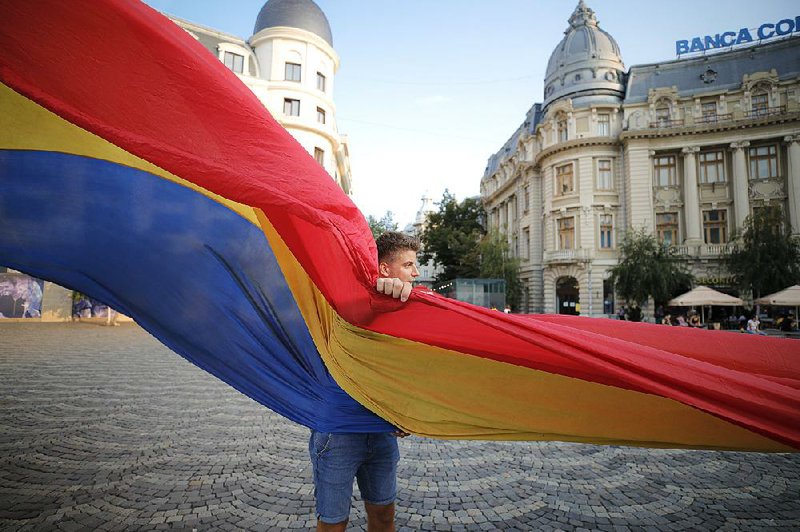 A youngster helps unfurl a roughly 330-foot Romanian flag in Bucharest on Monday as part of the country’s national anthem day.