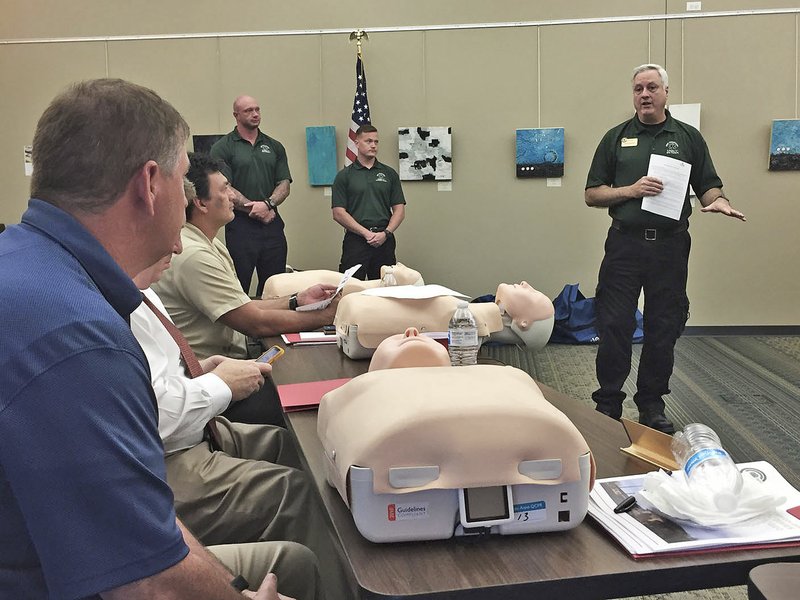 NWA Democrat-Gazette/DAVE PEROZEK Jamin Snarr (right), the EMT and paramedic program director at Northwest Arkansas Community College, leads college trustees Monday in a lesson on cardiopulmonary resuscitation during the board's summer retreat meeting in Bentonville.