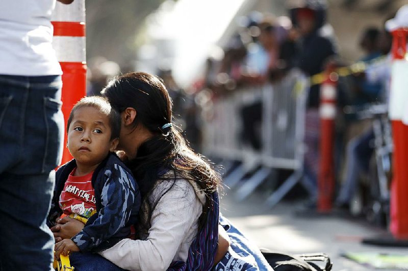 A woman waits with her sons in mid-July in Tijuana, Mexico, to apply for asylum in the United States. 