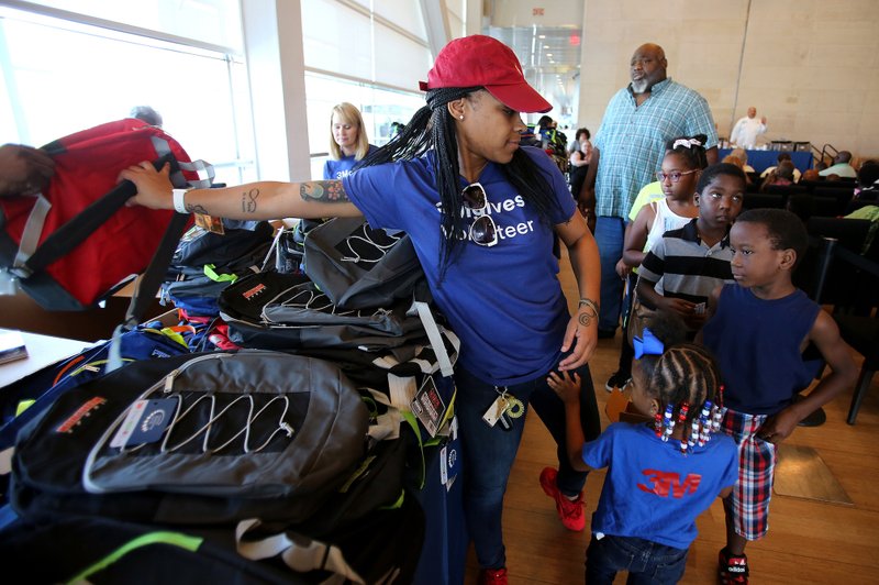 Volunteer Shonta Dobbins hands out backpacks at the Clinton Foundation's 2017 Head of the Class Bash. This year's bash will have an expanded list of services and a new location: the University of Arkansas at Little Rock's Jack Stephens Center. Democrat-Gazette file photo/Thomas Metthe