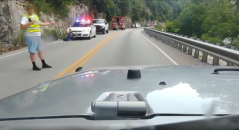 COURTESY PHOTO BY NICOLE RIDLEN/Emergency personnel guide traffic through Highway 59, between Noel and Ginger Blue, on Monday evening after a bicyclist discovered a deceased body and a suitcase discarded down a steep incline.