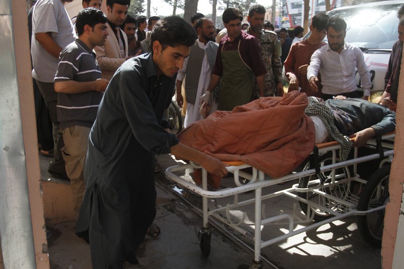 Afghans assist a wounded man in a hospital after a roadside bomb on the main highway between the western city of Herat and the southern city of Kandahar, in Herat, Afghanistan, Wednesday, July 31, 2019. A roadside bomb tore through a bus in western Afghanistan on Wednesday, killing at least 32 people, including children, a provincial official said. (AP Photo/Hamed Sarfarazi)