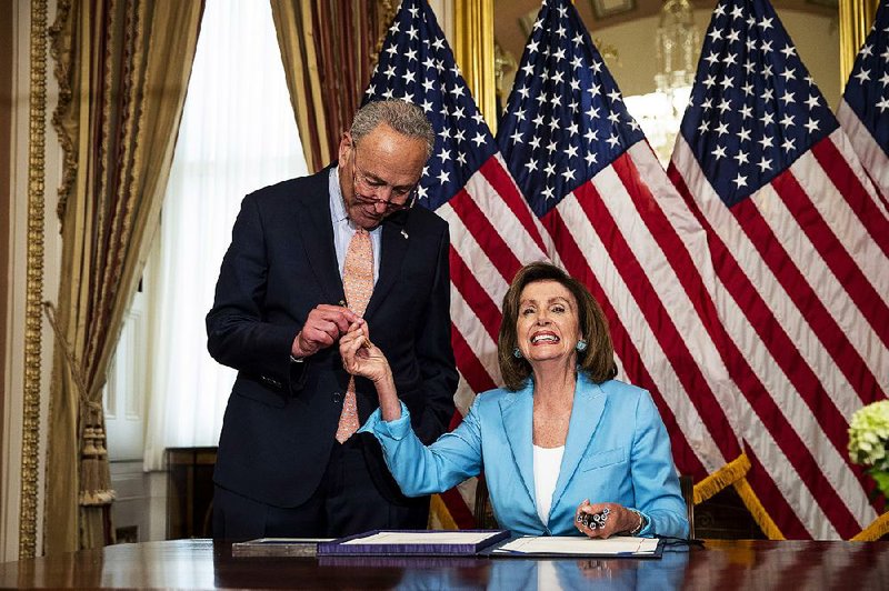 House Speaker Nancy Pelosi hands off the pen to Senate Minority Leader Charles Schumer as they sign the two-year budget agreement Thursday on Capitol Hill. 