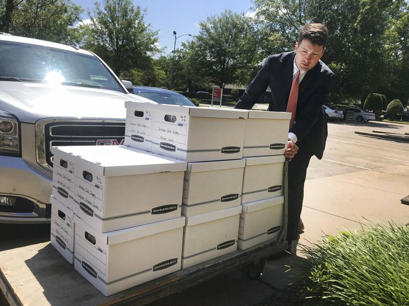 In this Tuesday, July 23, 2019, photo, Alex Gray, an attorney for Safe Surgery Arkansas, delivers petitions to the Arkansas secretary of state's office in favor of holding a referendum on a state law that expands the type of procedures optometrists can perform. (AP Photo/Andrew DeMillo)