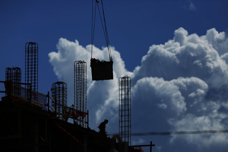 FILE - In this July 2, 2019, file photo a construction worker walks atop a building as a crane lifts a load over head in Miami. On Friday, Aug. 2, the U.S. government issues the July jobs report. (AP Photo/Brynn Anderson, File)

