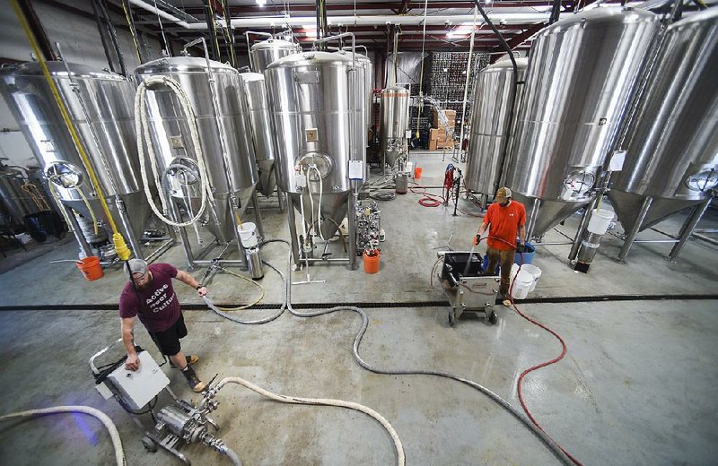 Brewers Brock Carson (left) and Brant Bishop work at Ozark Beer Co. in Rogers in this July 2019 file photo.