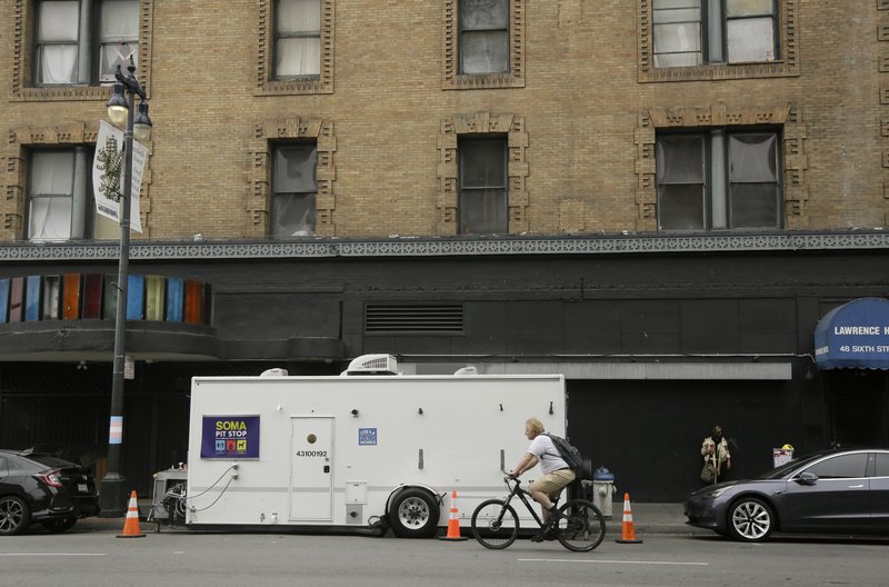 A man rides his bicycle past a "Pit Stop" public toilet on Sixth Street, Thursday, Aug. 1, 2019, in San Francisco.  (AP Photo/Eric Risberg)