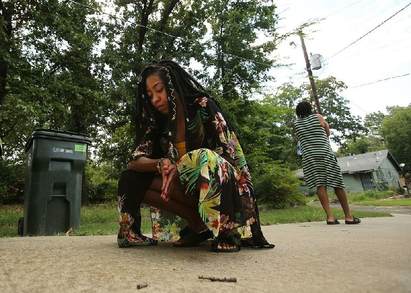 Marika Collins kneels Saturday on a driveway near the alley where her uncle, Wiley Carr, was fatally shot in January. Collins, looking at a stain on the concrete, said: “It looks like a bloodstain. I know it’s his.” 