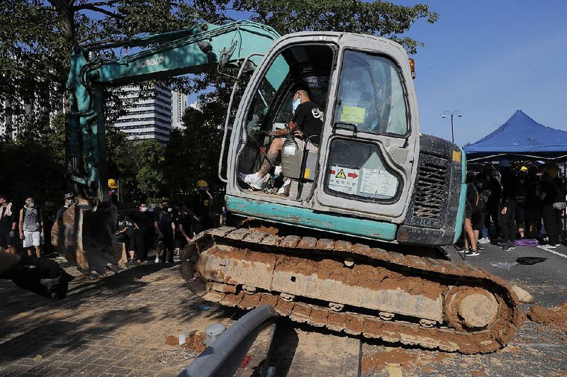 A protester uses construction equipment to block a road in Hong Kong on Monday. Protesters filled public parks and squares in several Hong Kong districts. 
