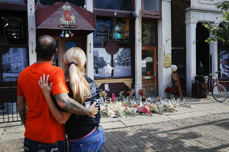 Mourners pause at a memorial to shooting victims Tuesday outside the Ned Peppers bar in Dayton, Ohio, where Connor Betts, 24, opened fire early Sunday. Investigators haven’t reported a motive for the attack, but his mental condition is being explored. 