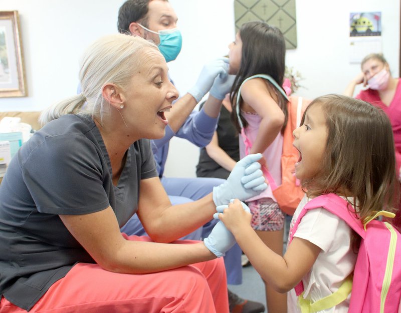 LYNN KUTTER ENTERPRISE-LEADER Tracy Orr with River Dental in Farmington tells Lilianna Acosta, 4, of West Fork, to open wide at the Farmington Back-to-School Bonanza last week. Farmington served 588 children. See more photos on Page 7A.